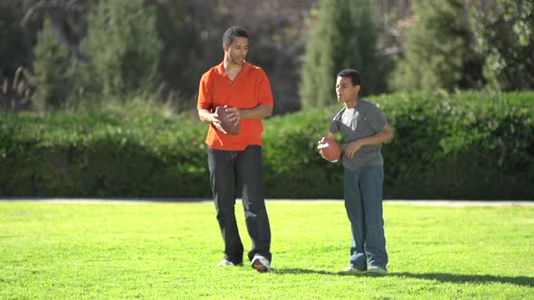 A father teaching his sons how to play American football.