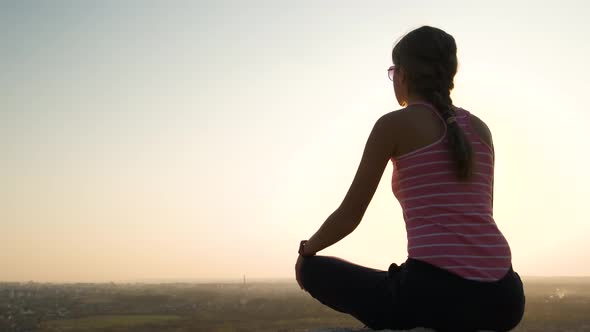 Young Relaxed Woman Sitting Outdoors on a Big Stone Enjoying Warm Summer Day