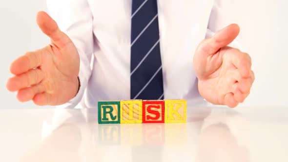 Businessman showing the word risk with alphabet block