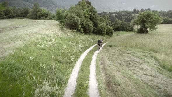 Aerial view of two cyclists riding bike in the forest on dirt road at Slovenia.