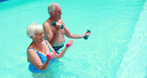 Senior couple exercising with dumbbells in the pool