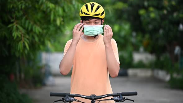 A young man riding a bicycle, wearing a helmet and wearing a medical mask.Slow motion footage.