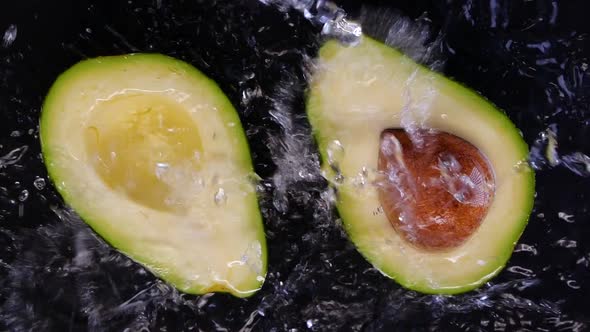 Avocado splashing into the water on black background.