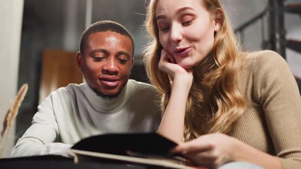 AfricanAmerican Bearded Man Turns Page of Album with Woman