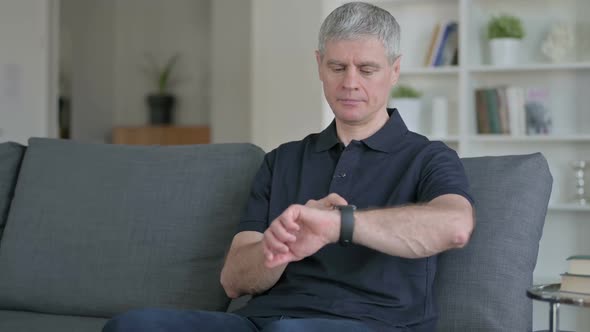 Relaxed Middle Aged Businessman Using Smartwatch at Home