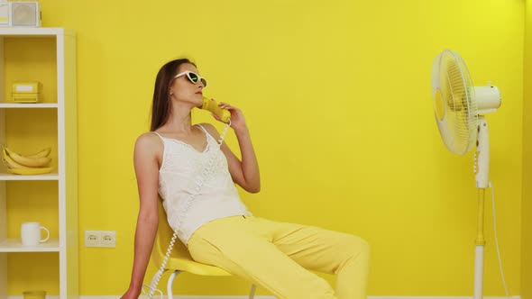 Woman Is Sitting In Chair and Talking On Retro Telephone