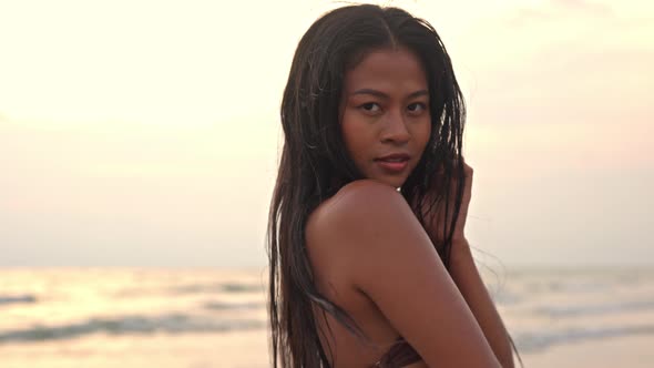 Beautiful Young Woman Looking At Camera On Beach At Sunset