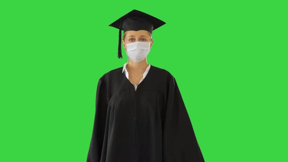 Female Graduate in Cap and Gown Wearing Medical Mask Walking on a Green Screen, Chroma Key