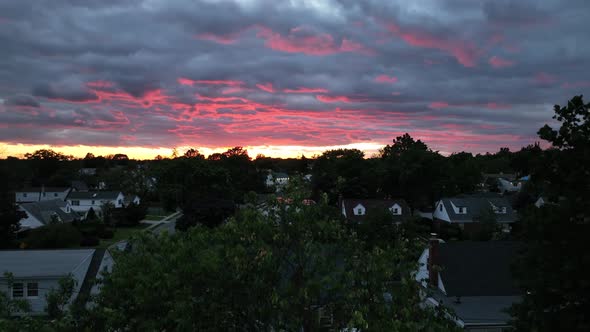 A drone view of a beautiful sunset from a suburban backyard. The neighborhood is getting dark as the