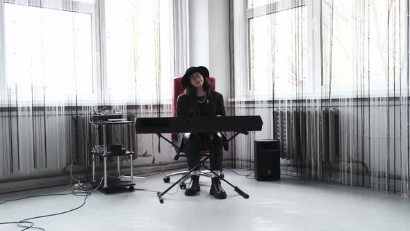 A Young Girl in a Hat is Practicing Piano in the Studio