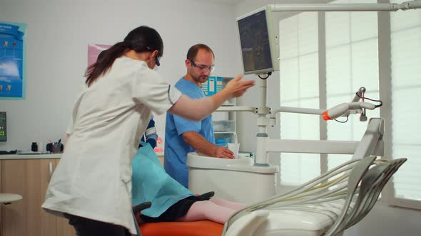 Stomatologist Pointing on Digital Screen Explaining Xray To Mother