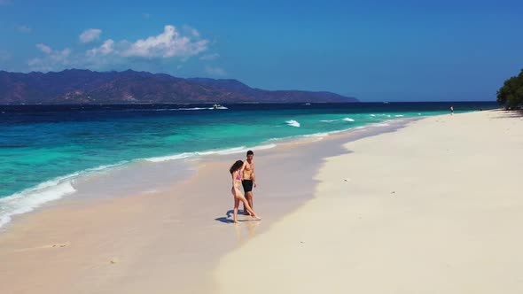 Teenage lovers tan on marine bay beach lifestyle by blue sea and white sandy background of Gili Meno