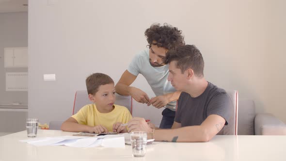 Two Dads Helping Focused Boy with School Home Task