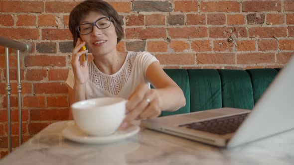 Woman Works Remotely in Cafe with Red Brick Walls