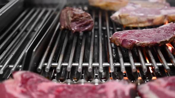Closeup, Dolly Shot of Delicious Meat Steaks Roasting on a Charcoal Barbecue Grill.