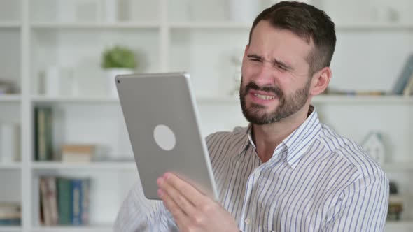 Portrait of Young Man Reacting To Loss on Tablet