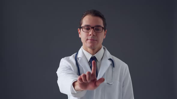 Studio portrait of young professional medical doctor standing over grey background