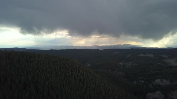 Aerial View of Storm Clouds Looming in the Distance in the Forested Mountains of Colorado, Tilt Down