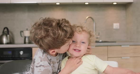 Adorable Brother and Sister Smile and Laugh Together While Sitting at the Kitchen Table Boy Hugs the