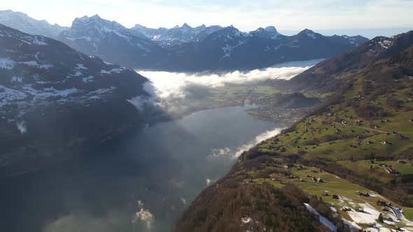 Aerial view of beautiful Swiss landscape with snow covered mountains, cloudscape and small villages