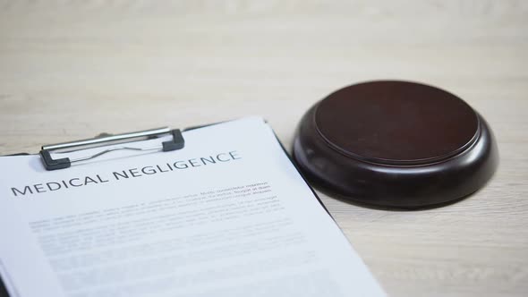 Medical Negligence Document on Table, Gavel Striking on Sound Block, Damage