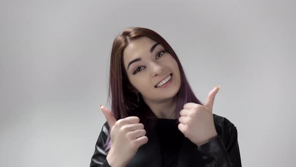 Portrait of Young Woman with Violet Hair Smiling and Showing Thumbs in the Studio