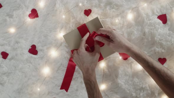 Close Up of Hands Preparing Red Bow for Gift Box