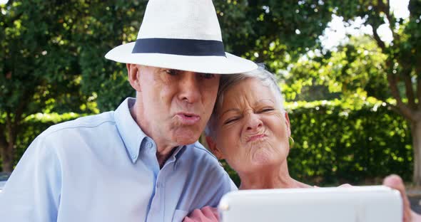 Senior couple taking selfie form mobile phone in park
