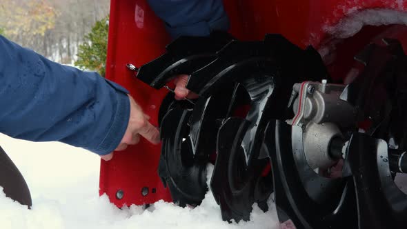 Man Repairs Blades on a Gas Powered Snow Blower