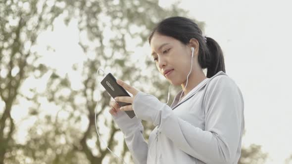 Runner athlete Asian woman using smartphone listening music jogging health lifestyle workout.