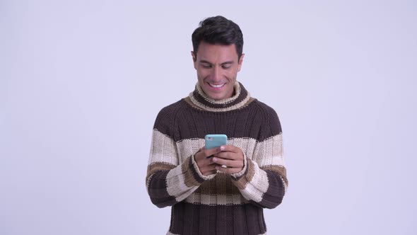 Young Happy Hispanic Man Using Phone Ready for Winter