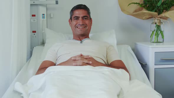 Front view of Caucasian male patient relaxing on hospital bed in hospital ward 4k