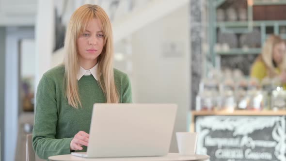 Beautiful Young Woman Reacting to Loss While Using Laptop in Cafe