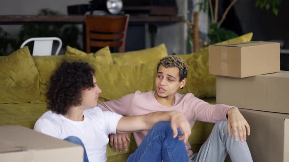 Homosexual Couple Talking in a New Apartment Around Boxes