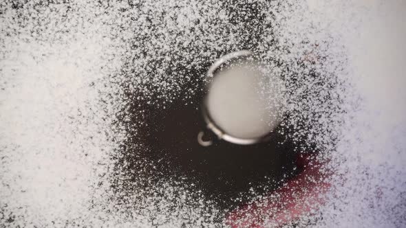 Sifting flour through a sieve onto a glass surface. Bottom view.