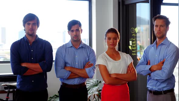 Confident business executives standing with arms crossed in office