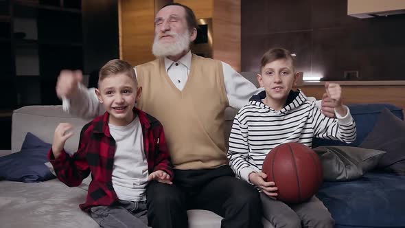 Boys and Their Retired Bearded Grandfather which Watching Sport Game on TV