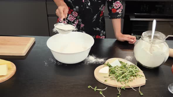 Sifting flour by sieve in bowl.