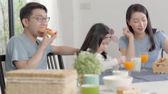 Parent and daughter eating Cereals with milk having breakfast morning in kitchen.