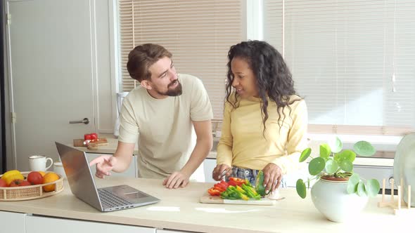 Happy Multiethnic Couple Cooking Together While Watching Cooking Tutorial