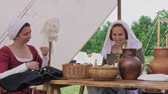 Group of people dressed in medieval clothes spending time together during sitting at the table.