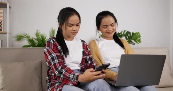 Asian twin girls playing smartphone on phone and using laptop