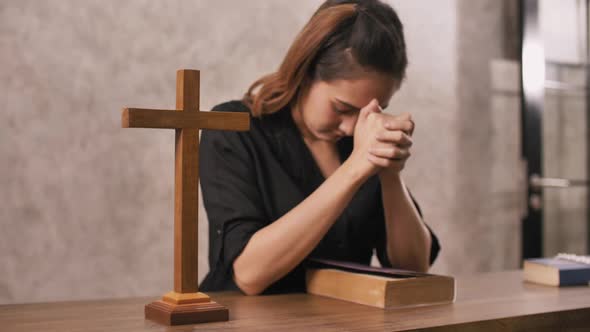 A young Asian Christian woman praying to Jesus Christ in a church.