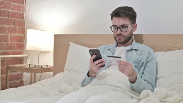 Attractive Male Designer Successful at Online Payment in Bed