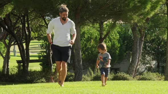 Handsome Runs with Cute Little Boy While Shooting with a Forest Behind