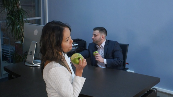 Young business people having lunch together, eating green apple