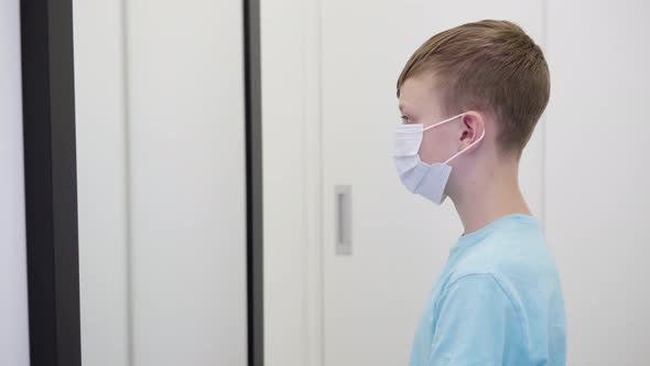 A Young Boy Puts on a Face Mask, Looks in Mirror Then Takes It Off in an Apartment