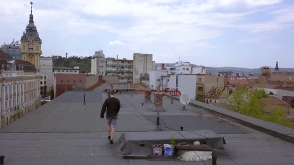 Tracking Shot of a Young Adult Male Walking on an Abandoned Roof Top.