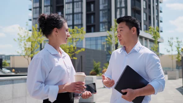 Korean Businessman Holding Laptop Talking to Business Partner