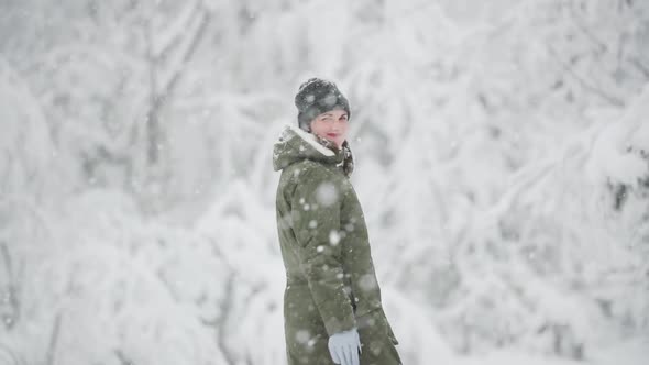 Young Beautiful Caucasian Girl Woman Dressed In Jacket Walking In Winter Forest In Snowy Day. Slo-mo